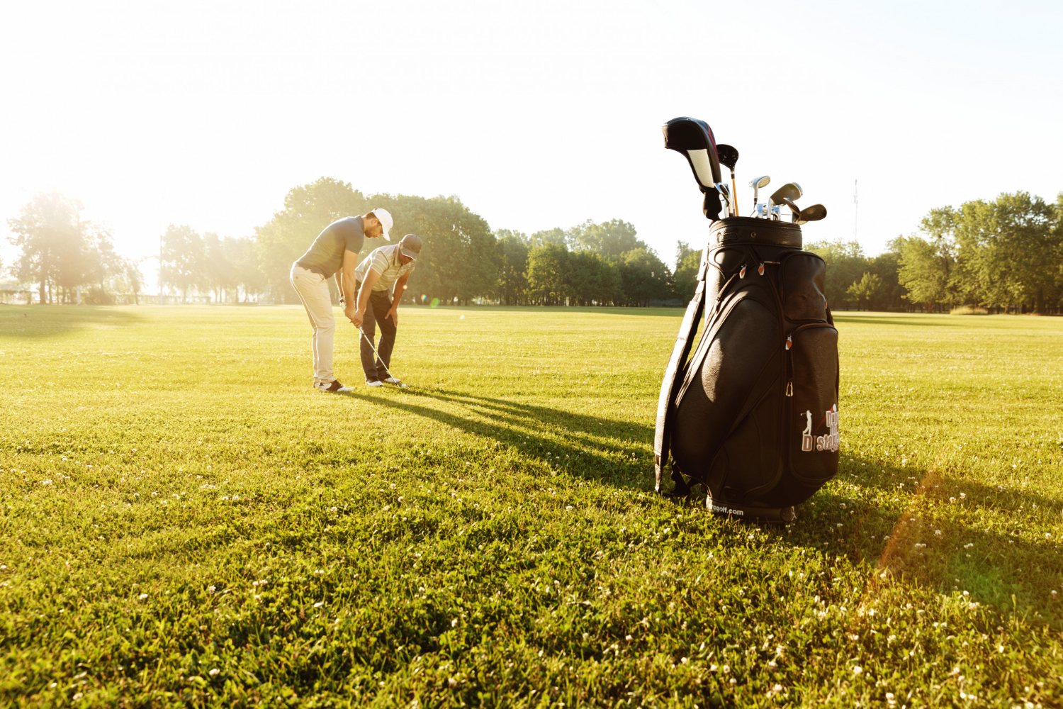 senior-male-coach-teaching-young-sportsman-how-to-play-golf